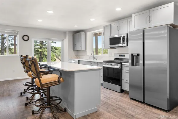 a kitchen with kitchen island a counter top space a sink stainless steel appliances and cabinets