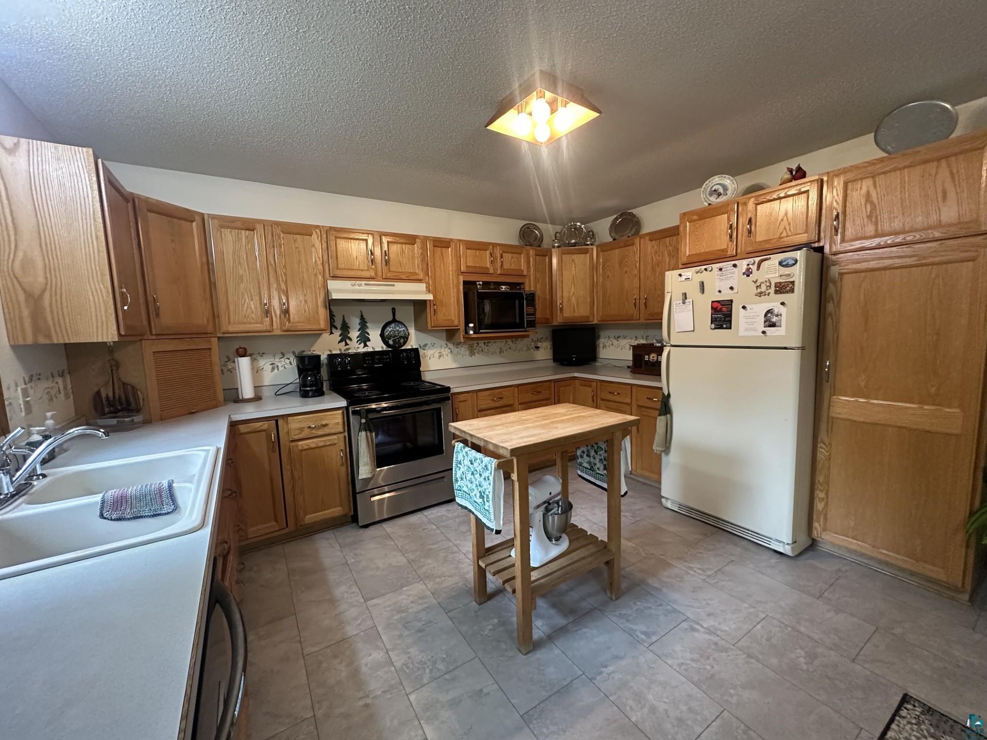 81 Hautaluoma Road Esko, MN 55733 - Photo 8 of 43 Functional kitchen featuring abundant wood cabinetry, light-toned countertops, and a double basin sink
