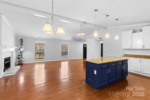 a kitchen with stainless steel appliances granite countertop wooden floors and a view of living room