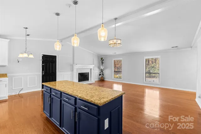 a kitchen with a stove center island a wooden floor and ceiling cabinets
