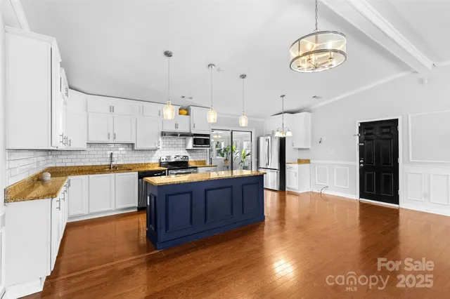 a large kitchen with stainless steel appliances granite countertop a sink dishwasher stove and oven with wooden floor