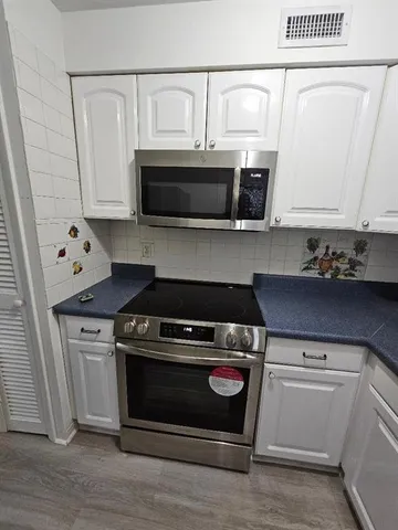 a kitchen with white cabinets and black appliances