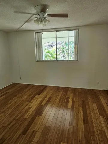 an empty room with wooden floor closet and windows