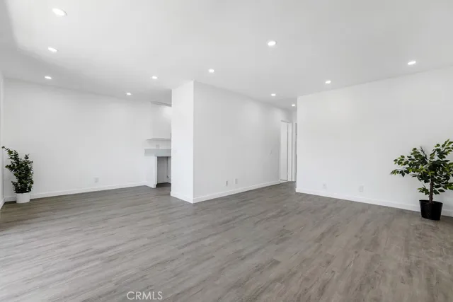 a view of an empty room with wooden floor and a potted plant