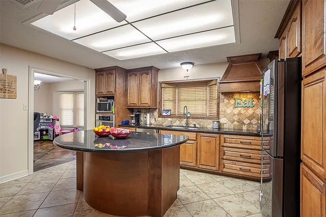 a kitchen with kitchen island granite countertop a sink stove and cabinets
