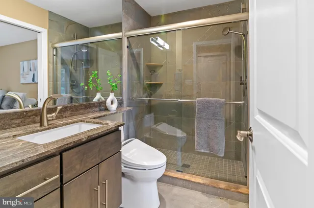 a bathroom with a granite countertop sink toilet and shower