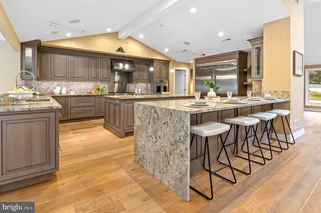 a kitchen with stainless steel appliances granite countertop a stove top oven a sink dishwasher and cabinets with wooden floor