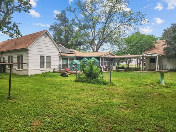 a view of a house with a yard and a large tree