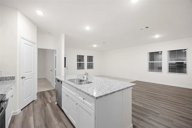 a hall with kitchen island granite countertop wooden floor and a sink