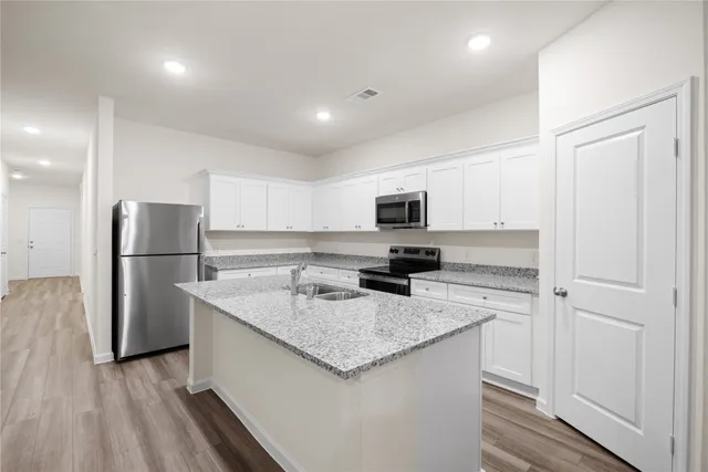 a kitchen with stainless steel appliances granite countertop a sink a refrigerator and a stove