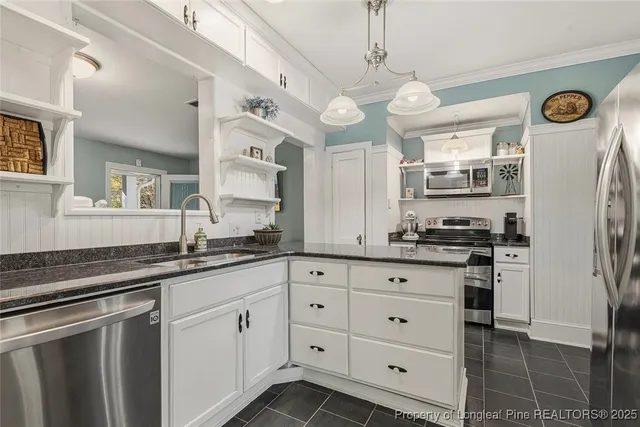 a kitchen with granite countertop a sink a stove a refrigerator and cabinets