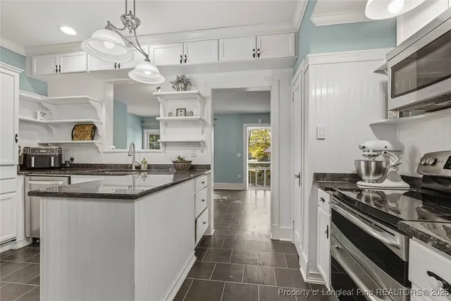 a kitchen with stainless steel appliances granite countertop a sink a stove and cabinets