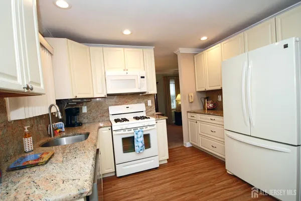 a kitchen with stainless steel appliances a stove a sink and white cabinets with wooden floor