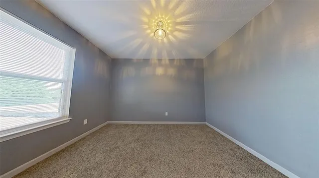 an empty room with a window and a fan