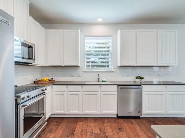 a white kitchen with granite countertop stainless steel appliances