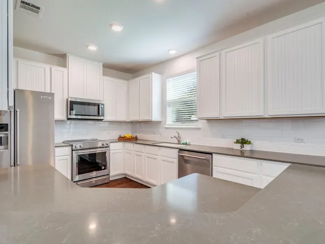 a kitchen with granite countertop white cabinets and a wooden floor
