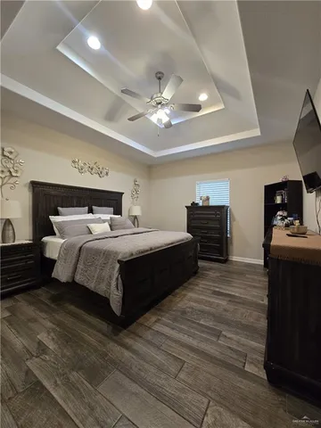 a bedroom with a bed ceiling fan and a dresser