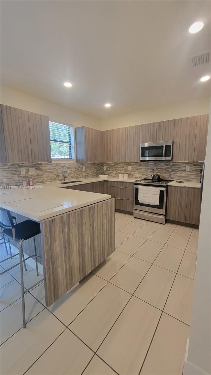 8860 Northwest 103rd Path Doral, FL 33178 - Photo 20 of 52 a kitchen with stainless steel appliances granite countertop a stove a sink and a refrigerator