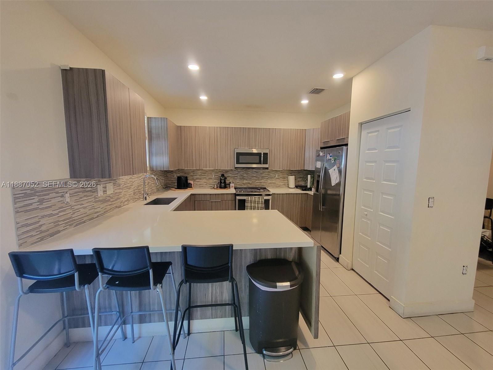 8860 Northwest 103rd Path Doral, FL 33178 - Photo 21 of 52 a kitchen with stainless steel appliances kitchen island granite countertop a refrigerator and a stove top oven