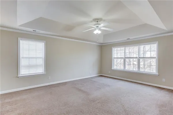 an empty room with chandelier fan and windows