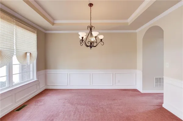 a view of an empty room with chandelier and window