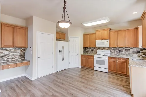 a kitchen with granite countertop white cabinets and white appliances