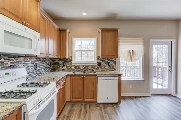 a kitchen with stainless steel appliances granite countertop wooden cabinets a stove a sink and a window