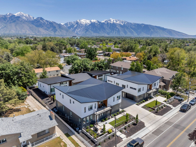 7045 South 300 East Midvale, UT 84047 - Photo 2 of 49 Modern architectural residences featuring contrasting white and dark grey exteriors, dark metal roofs, integrated garages, and structured landscaping