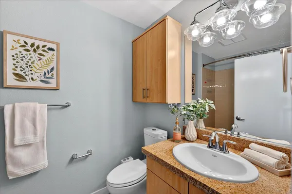 a bathroom with a granite countertop sink a mirror and a toilet