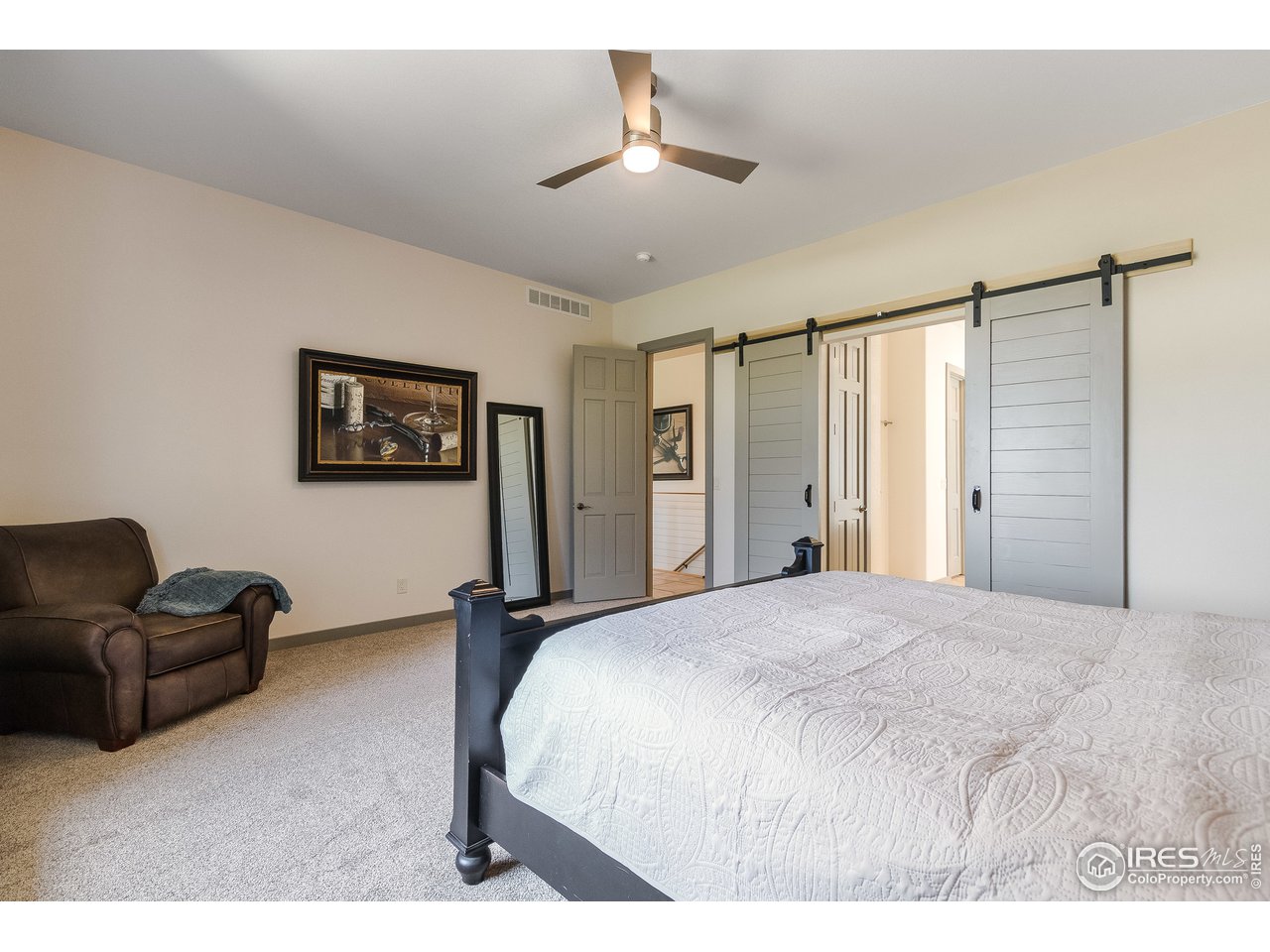 6586 Rookery Road Fort Collins, CO 80528 - Photo 17 of 39 a spacious bedroom with a bed a couch and a chandelier