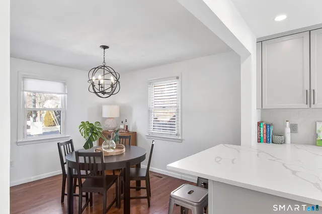 a kitchen with stainless steel appliances granite countertop a sink dishwasher a refrigerator white cabinets and wooden floor