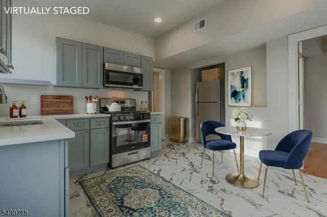 a kitchen with stainless steel appliances granite countertop a stove top oven a sink a dining table and chairs