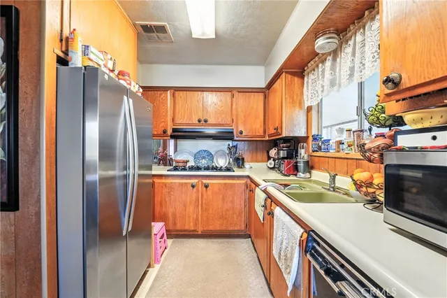 a kitchen with stainless steel appliances granite countertop a refrigerator a stove and a sink with cabinets