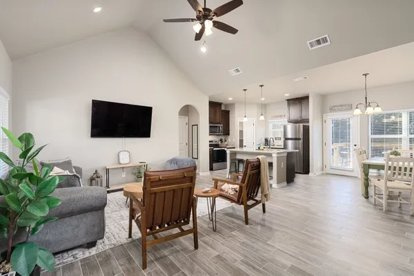 a living room with furniture kitchen view and a flat screen tv