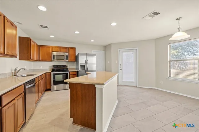 a kitchen with kitchen island granite countertop stainless steel appliances cabinets a sink and a window
