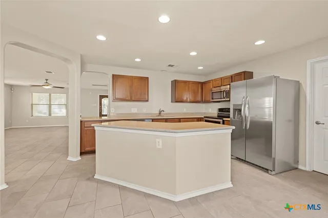 a large kitchen with stainless steel appliances granite countertop a refrigerator a sink a stove and a refrigerator