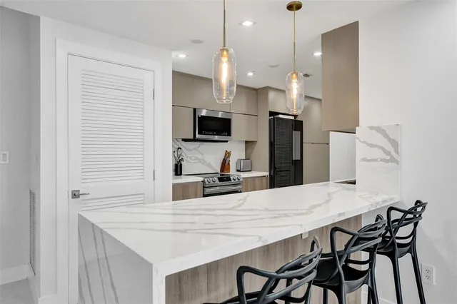 a kitchen with kitchen island a refrigerator a stove a sink and chairs