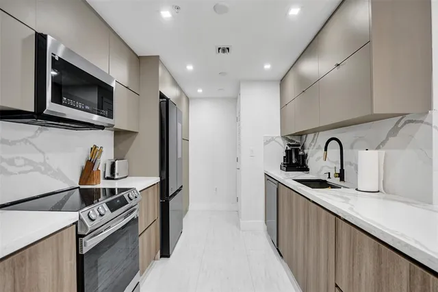 a kitchen with stainless steel appliances granite countertop a sink and a stove top oven with wooden floor