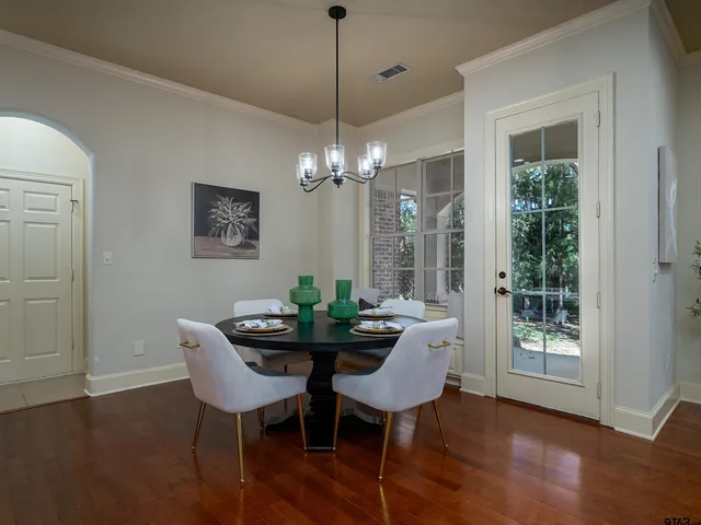 a dining room with furniture wooden floor a chandelier and a mirror