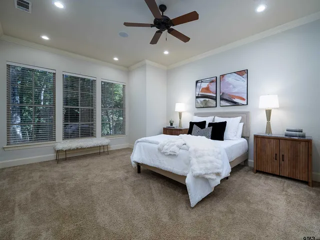 a spacious bedroom with a bed painting on wall and a large window