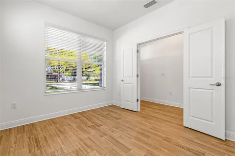a view of an empty room with wooden floor and a window