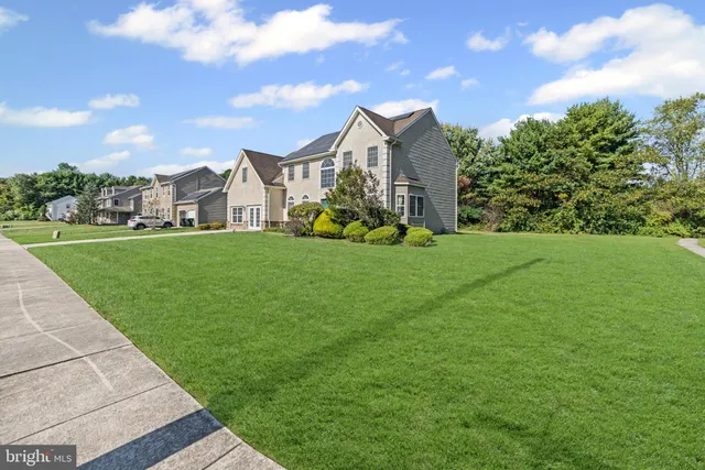 a view of a house with a big yard and large trees