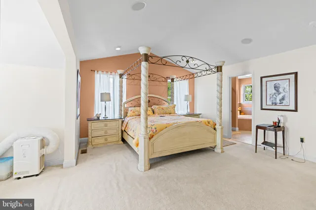 a spacious bedroom with a bed a dresser and windows