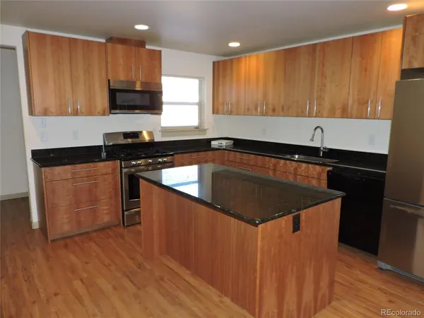 a kitchen with kitchen island granite countertop wooden cabinets a sink and a stove