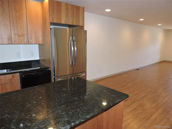 a kitchen with stainless steel appliances granite countertop a refrigerator a stove and a refrigerator with wooden floor