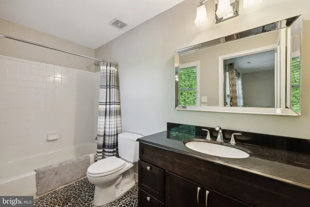 a spacious bathroom with a granite countertop double vanity sink a mirror and shower