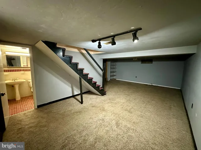 a view of an empty room with stairs and a living room