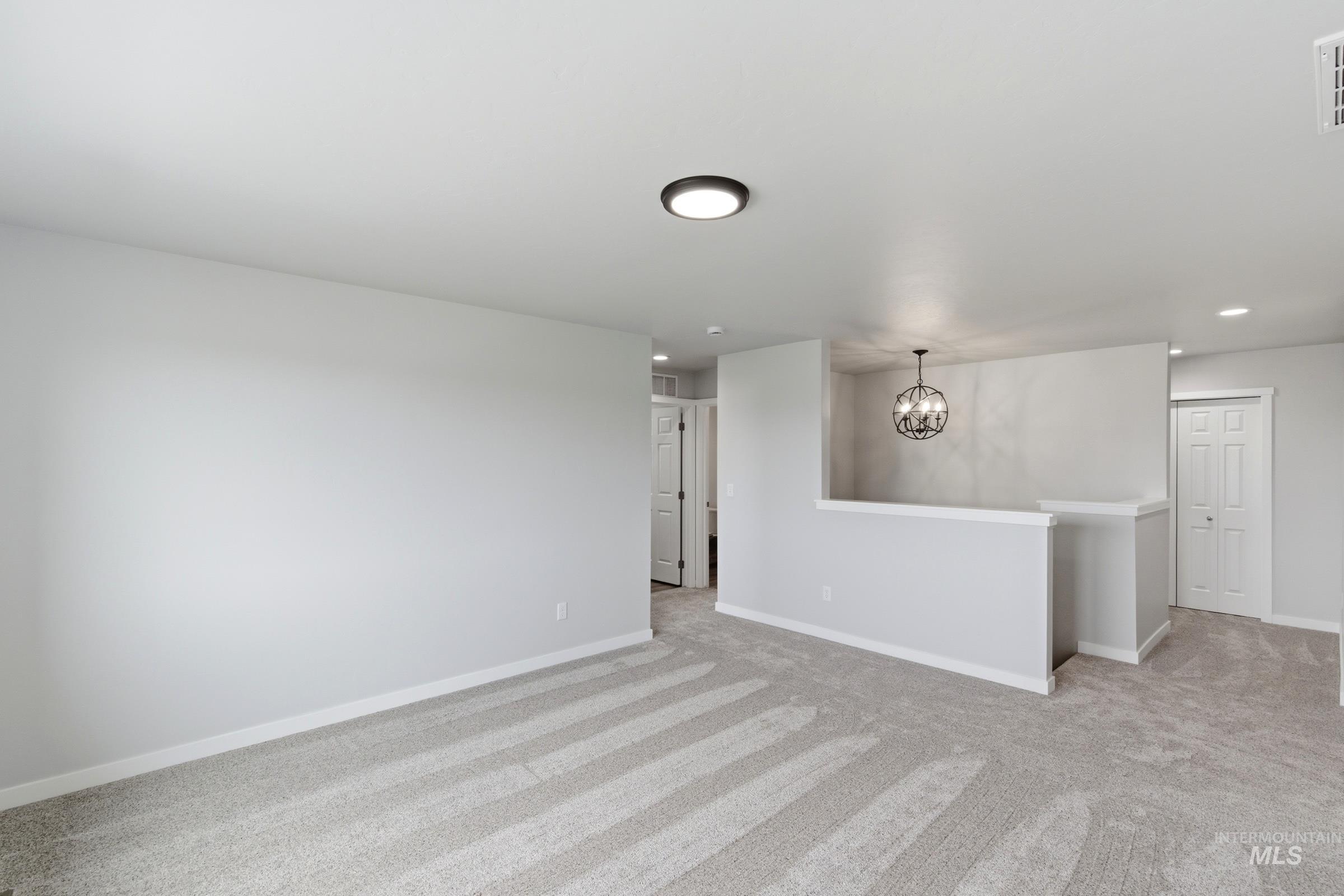 16558 Dunning Way Caldwell, ID 83607 - Photo 18 of 35 Carpeted open-concept space featuring light gray walls, white trim, and a contemporary flush-mount ceiling light