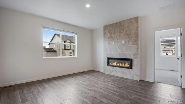 an empty room with wooden floor a fireplace and windows