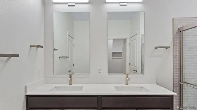 a bathroom with double sink and two mirror